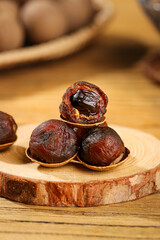 Dried Longan Fruit with Cinnamon Brown Shells Showing Sweet Dark Meat Core Detail on Wood