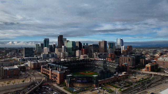 Aerial view of the iconic Coors Field baseball stadium nestled among the modern skyscrapers under a vast, expansive sky, Denver, Colorado, United States.
