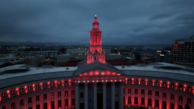 Aerial view of the Denver City and County Building illuminated in vibrant red against the encroaching twilight, Denver, Colorado, United States.