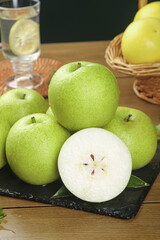 Fresh Green Pears on Slate Board with Cut Half Showing Interior on Wooden Table