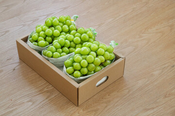 Fresh Green Grapes in Cardboard Packaging Box on Wood Table