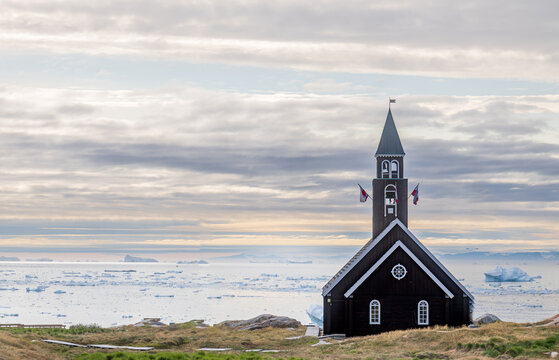 Wooden church with icebergs in background at Ilulissat Greenland