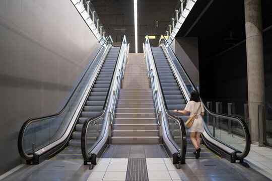 Woman using escalator in modern urban metro station
