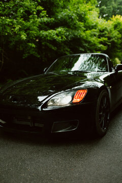Sleek black convertible in lush forest setting