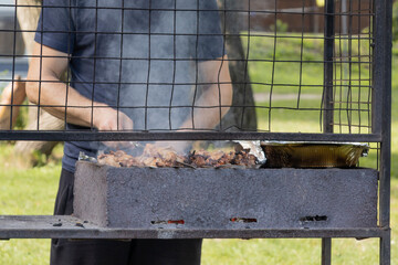 Man cooking a juicy slices of meat prepare on the fire. Tasty shish kebab on skewers. Grilled...
