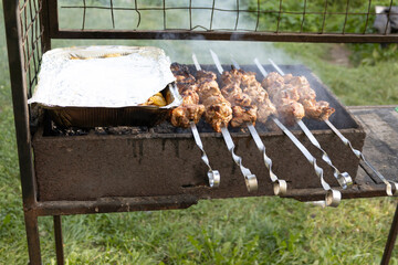 Juicy slices of meat prepare on the fire. Stewed potatoes in foil.Tasty shish kebab on skewers....
