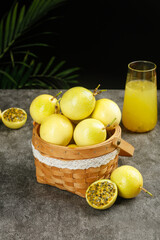 Fresh Golden Passion Fruits in Wicker Basket with Tropical Juice Glass on Stone Surface