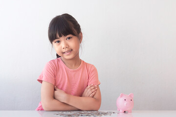 Cute little asian girl with Piggy Bank, putting coins, or thinking or showing thumbs up. Concept of...