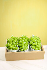 Fresh Green Grapes in Paper Bags on Yellow Background - Healthy Organic Fruit Display