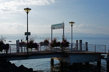 Ponton en bois sur un lac au soleil couchant en fin de journée de vacances d'été. Embarcadère pour bateau de croisière et navette maritime.