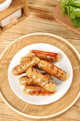 Delicious Grilled Sausages on White Plate with Rustic Wooden Kitchen Background