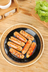 Grilled Sausages in Black Pan on Wooden Table with Fresh Lettuce - Delicious Meal Preparation