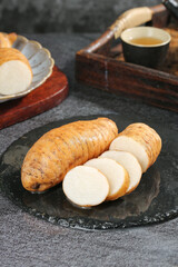 Fresh Yunnan Mountain Asparagus Roots Sliced on Stone Plate with Traditional Chinese Tea Service