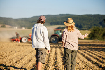 Farmers looks at tractor sowing in field and agricultural cultivation