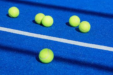 Several yellow tennis balls scattered across a blue padel court The Aftermath of a Training Session