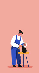 Fototapeta premium Professional pet groomer brushes a black cat on a stool, illustrating dedicated pet care, pampering, and animal welfare. Useful for pet services or lifestyle content.