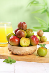Fresh Colorful Plums in Wicker Basket with Juice Glass on Wooden Board