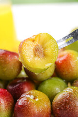 Fresh Plum Cut in Half with Knife Revealing Golden Flesh and Pit Among Colorful Stone Fruits