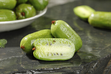 Fresh Green Kiwi Berries Cut in Half Showing Seeds and Soft Flesh on Dark Slate Surface