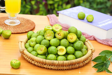 Fresh Green Plums in Wicker Basket - Stone Fruit Display on Wooden Table