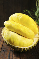 Fresh Durian Fruit with Golden Flesh Exposed in Spiky Shell on Wooden Table