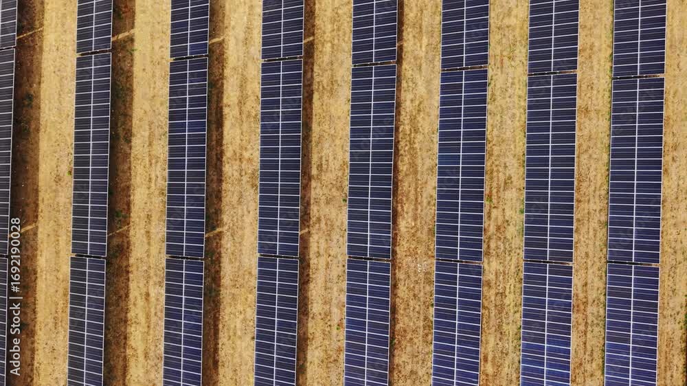 Poster drone forward shot in total overhead view of solar panels and dry soil field in sicily.