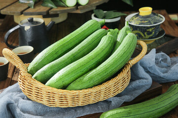 Fresh Long Green Squash Vegetables in Wicker Basket on Wooden Kitchen Table