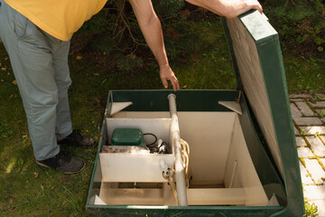 Man checking modern septic tank system outdoors.