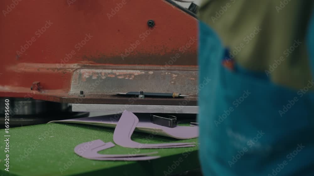 Poster close up of worker using machine to cut leather shoe patterns