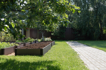 Private backyard garden with trees and raised beds prepared for planting, ideal for eco-friendly,...