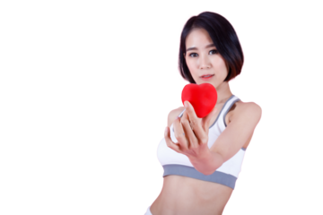 Concept of healthy living: a fit woman holds a heart, promoting well-being, charity, and self-love. A young woman in a sports bra holds a red heart symbol, representing health, love, and care.