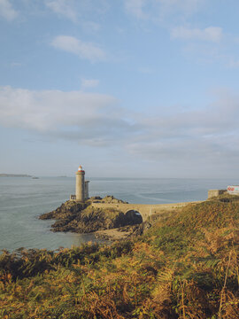 View of the Petit Minou lighthouse standing guard on a rocky outcrop kissed by the sea, with golden vegetation in the foreground, Plouzan&Atilde;&copy;, France.
