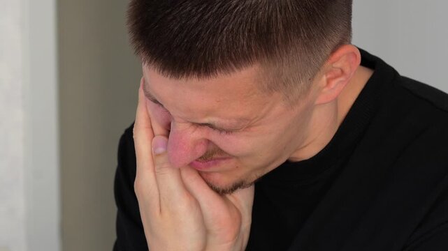 A patient with sore teeth stands in a room and holds his cheek with his hand.
Suffering from toothache in the mouth.
A man suffers from toothache