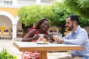 Couple enjoying coffee and using smartphone at outdoor cafe