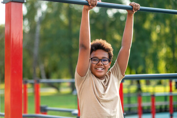 Fototapeta premium Curly-haired boy in eyeglasses spending time at the playground