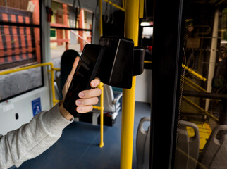woman using smartphone to pay for public bus ride