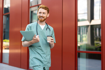 Man doctor with beard walking in scrubs holding coffee and folder