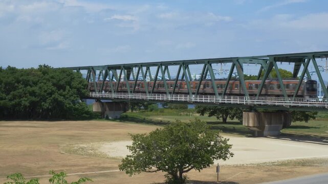 Train Crossing On The Railroad Bridge Over Yodogawa Riverside National Park In Nagara, Osaka, Japan. - wide shot