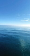 Obraz premium Calm, vast expanse of deep blue sea meeting a clear, pale blue sky