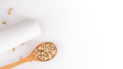Tube of cream and wooden spoon with oatmeal on light background, skincare concept with copy space, real photo 16:9.