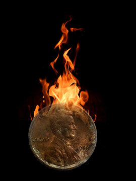 One old, antiquated penny burning in flames