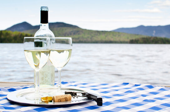 Two glasses and bottle of white wine on table on lakeshore
