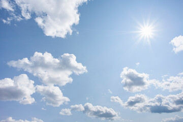 Bright sunshine and white puffy clouds in blue sky