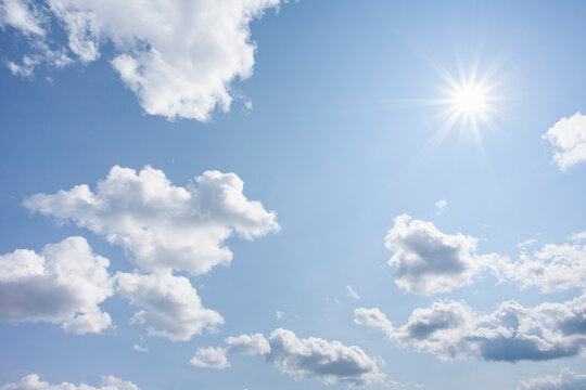 Bright sunshine and white puffy clouds in blue sky