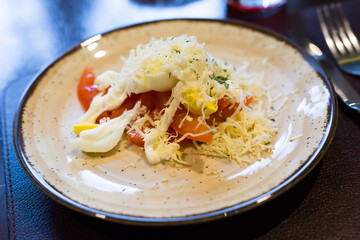 plate with a mix of tomatoes, cheese, eggs with french sauce