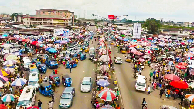 Aerial view of a bustling market scene with vibrant umbrellas lining the Kilometer 14 Road under a cloudy sky, Elelenwa, Port Harcourt, Nigeria.