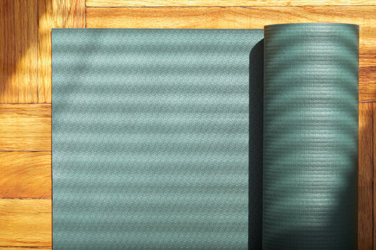 Overhead view of partially rolled yoga mat on wooden floor
