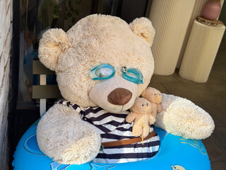 Funny large teddy bear with goggles, striped shirt and inflatable ring. Whimsy, childhood joy and...