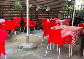 Outdoor dining courtyard with red chairs and checkered tablecloths. Hospitality, leisure and...