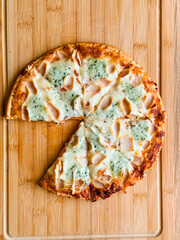 Sliced pizza with visible pieces and toppings on wooden board. Sharing, leisure and culinary...